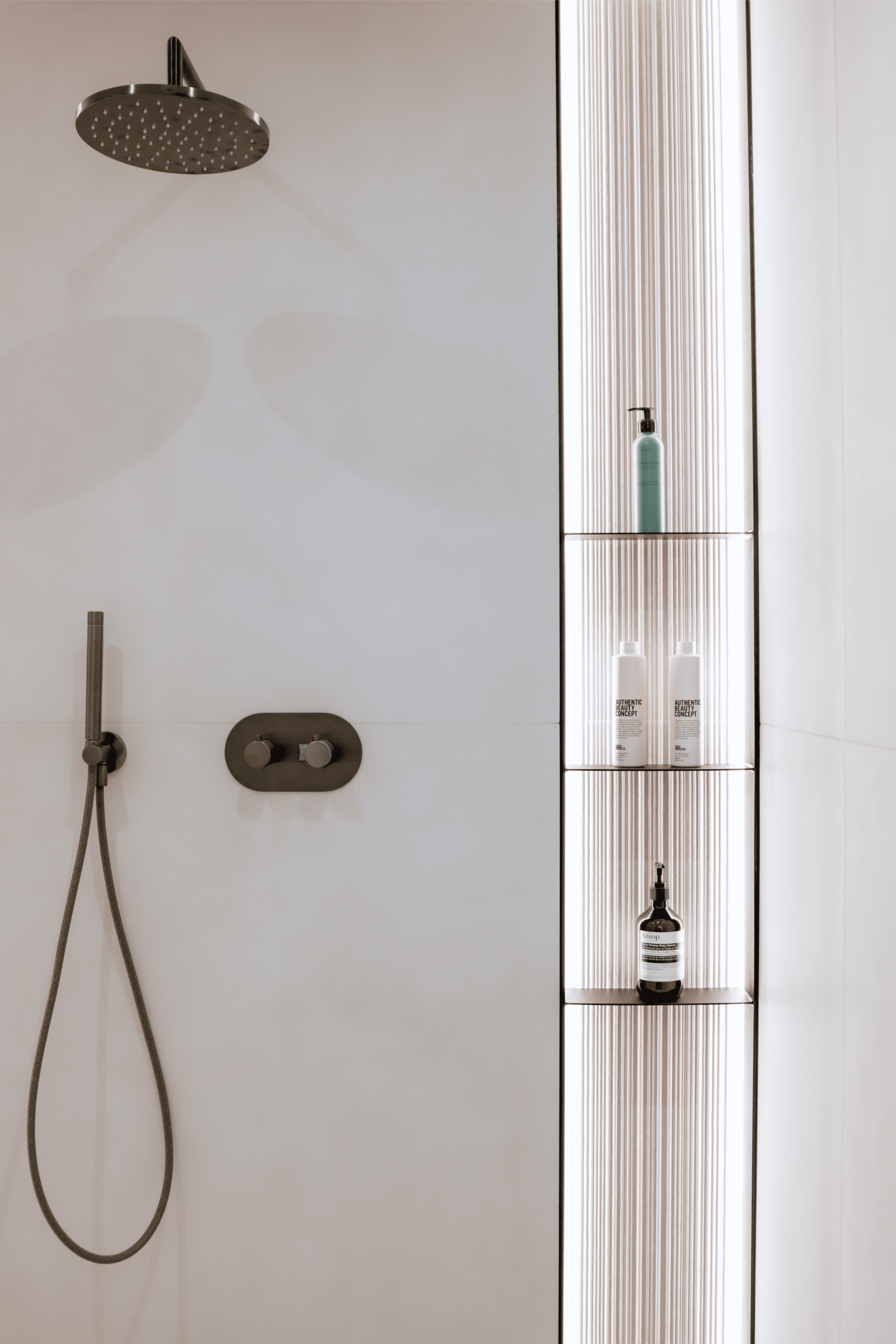 Douche avec robinetterie noire mate et niche de rangement carrelée, appartement à Liège